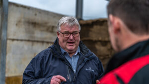 David Watson mid lively conversation with farmer whose back is to camera, in silage clamp